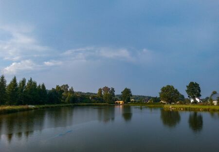 Summer landscape with lake and trees in stormy dayの写真素材