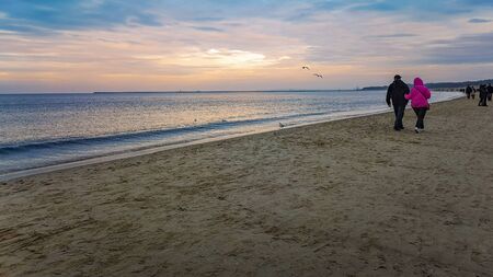 People walking on beach near water over Baltic Sea in Swinoujscie at novemberの写真素材