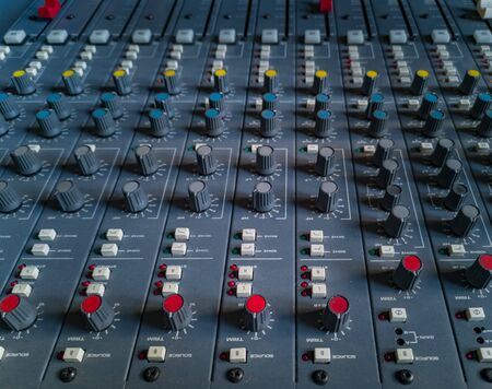 Front panel of old music radio console with colorful potentiometers and sliders