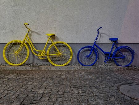 Yellow and blue bike leaned againist the wallの写真素材
