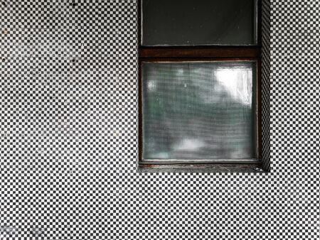 Old covered window at facade of mosaic black and white tilesの写真素材