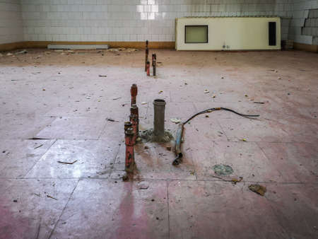 Water pipes in floor in old kitchen and doors leanded against the wall in old abandoned hospitalのeditorial素材
