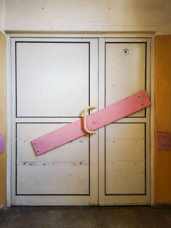 White bolted doors by pink board in old abandoned hospitalの写真素材