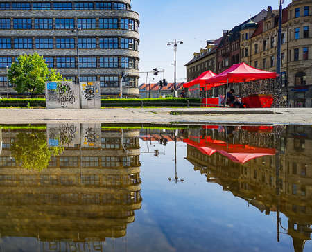 Wroclaw June 14 2019 Renoma shopping mall and red tents with sunglasses reflected in large puddleのeditorial素材