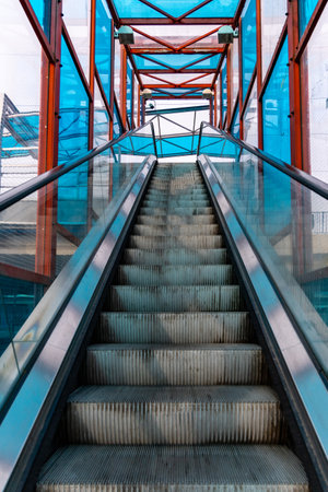 Long escalator to bridge over street with colorful windows aroundの写真素材