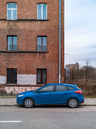 Lodz, Poland - February 22 2020 Blue car standing in front of old red brick buildingのeditorial素材