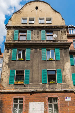 Walbrzych, Poland - June 15 2020: Facade of old tenement house with green shutters outside