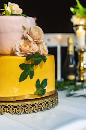 Pink and yellow wedding cake standing on table with colorful and beauty decorations aroundの写真素材
