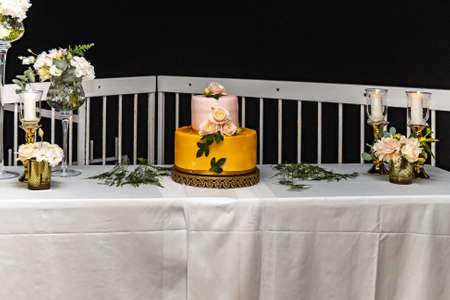 Pink and yellow wedding cake standing on table with colorful and beauty decorations aroundの写真素材