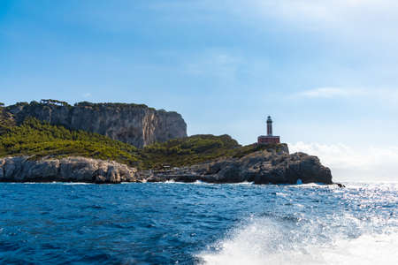 Capri, Italy - August 24 2020: High lighthouse on the edge of high cliff seen from boat
