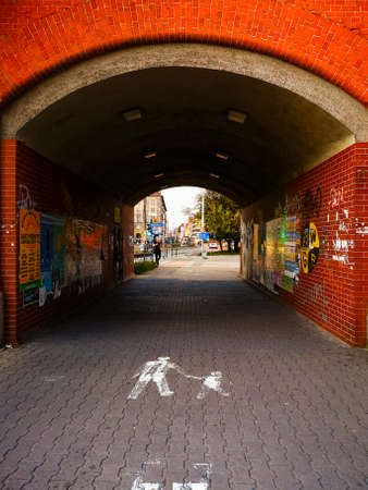 Wroclaw, Poland - September 7 2020: Entrance to small tunnel made of red brick and full of posters under the railroadのeditorial素材
