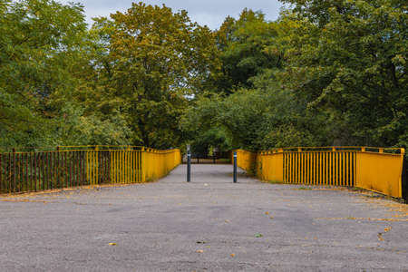 Small concrete bridge with yellow railings and trees aroundの写真素材
