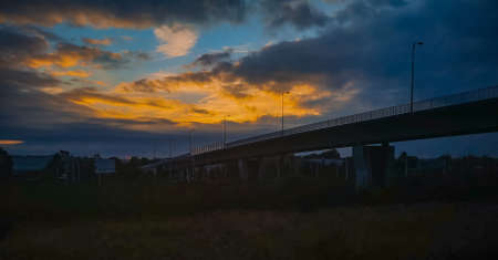 Wroclaw, Poland - October 9 2020: Beautiful cloudy sunset over long traffic bridge seen from train