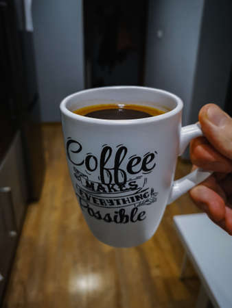 White cup of coffee with writings on it in long corridorの写真素材
