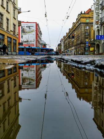 Wroclaw, Poland - December 23 2020: Cityscape of Pilsudskiego street with riding tram reflected in puddleのeditorial素材