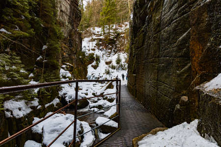 Small footbridge over mountain river between high rocks as path to waterfallの写真素材