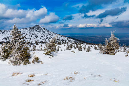 Snowy landscape of mountain trails and hills at cloudy morningの写真素材