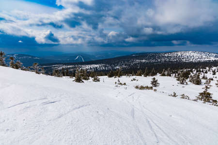 Snowy landscape of mountain trails and hills at cloudy morningの写真素材