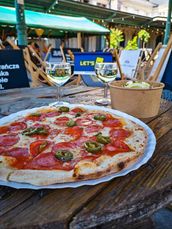 Wroclaw, Poland - June 2021: Box of pasta salad and pizza with two glasses of white wine in outdoor restaurantのeditorial素材
