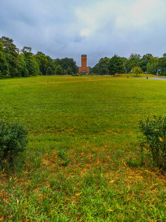 Wroclaw, Poland - August 2021: Big green glade at center of district in front of red brick church with high towerの写真素材