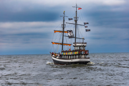 Kolobrzeg, Poland - October 2021: Modern pirate ship for tourist trips goes on a cruise at stormy...
