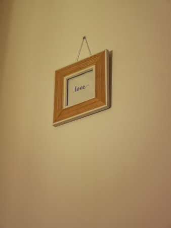Small square wooden frame hung on the wall with Love word inside