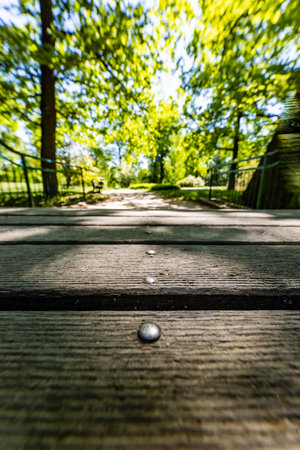 Old renovated retro bridge with green metal railings over small river in small colorful park at sunny morningの写真素材