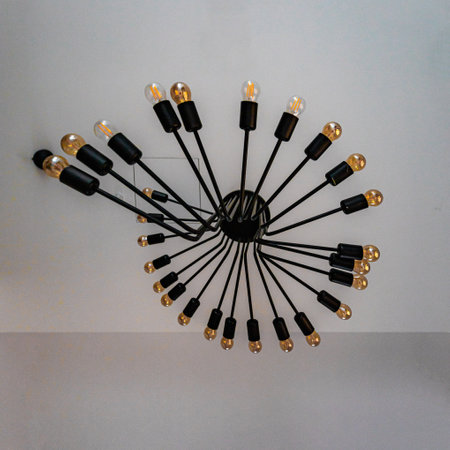 A large black chandelier full of golden decorative light bulbs, seen from belowの写真素材