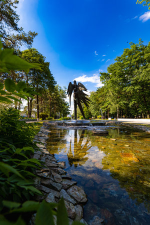 Stalowa Wola, Poland - June 2022: A beautiful, colorful city park with an artificial river, a fountain and walking people on a sunny dayのeditorial素材