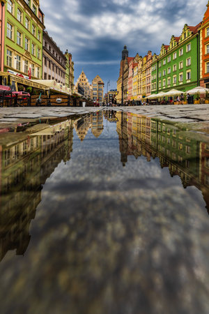 Wroclaw, Poland - July 2022: Wroclaw market square old tenement houses reflected in small puddleのeditorial素材