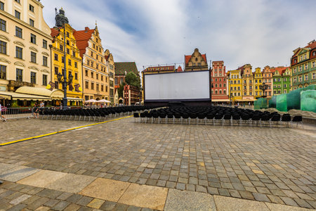 Wroclaw, Poland - July 2022: Outdoor cinema at market square with giant scene and white screen with a lot of black, plastic chairsのeditorial素材