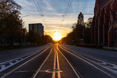 Wroclaw, Poland - October 2022: Beautiful setting sun at sunset just above center of the long Grabiszynska street with tram rails and riding cars and tramのeditorial素材