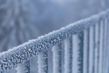 Metal railings of viewing tower covered with a lot of snow and ice faced to one side by strong windの写真素材
