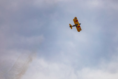 Leszno, Poland - June 16 2023: Antidotum Airshow Leszno 2023 and acrobatic shows of yellow Boeing Stearman plane on a blue cloudy skyのeditorial素材