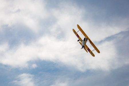 Leszno, Poland - June 16 2023: Antidotum Airshow Leszno 2023 and acrobatic shows of yellow Boeing Stearman plane on a blue cloudy skyのeditorial素材