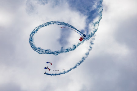 Leszno, Poland - June 16 2023: Antidotum Airshow Leszno 2023 and show of PHENIX Ambassadeurs Parachutistes flying down on parachutes with french and polish flag and a lot of smokeのeditorial素材