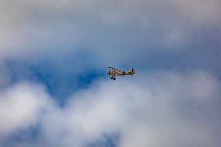 Leszno, Poland - June 16 2023: Antidotum Airshow Leszno 2023 and acrobatic shows of yellow Boeing Stearman plane on a blue cloudy skyのeditorial素材