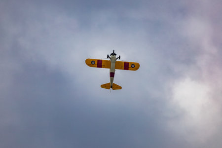Leszno, Poland - June 16 2023: Antidotum Airshow Leszno 2023 and acrobatic shows of yellow Boeing Stearman plane on a blue cloudy skyのeditorial素材