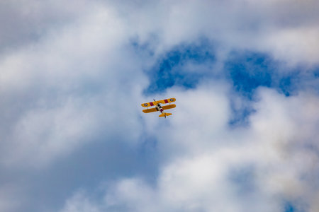 Leszno, Poland - June 16 2023: Antidotum Airshow Leszno 2023 and acrobatic shows of yellow Boeing Stearman plane on a blue cloudy skyのeditorial素材