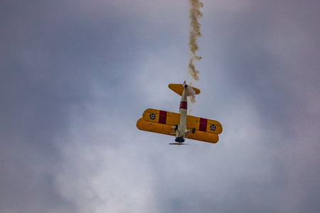 Leszno, Poland - June 16 2023: Antidotum Airshow Leszno 2023 and acrobatic shows of yellow Boeing Stearman plane on a blue cloudy skyのeditorial素材