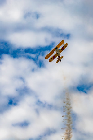 Leszno, Poland - June 16 2023: Antidotum Airshow Leszno 2023 and acrobatic shows of yellow Boeing Stearman plane on a blue cloudy skyのeditorial素材