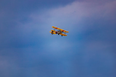 Leszno, Poland - June 16 2023: Antidotum Airshow Leszno 2023 and acrobatic shows of yellow Boeing Stearman plane on a blue cloudy skyのeditorial素材