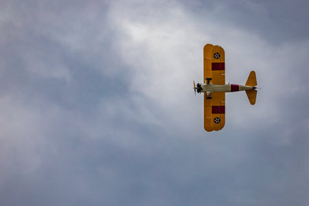 Leszno, Poland - June 16 2023: Antidotum Airshow Leszno 2023 and acrobatic shows of yellow Boeing Stearman plane on a blue cloudy skyのeditorial素材