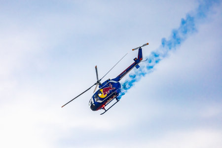Leszno, Poland - June 16 2023: Antidotum Airshow Leszno 2023 and acrobatic shows full of smoke of Felix Baumgartner flying by helicopter Red Bull Bo 105 on a cloudy skyのeditorial素材