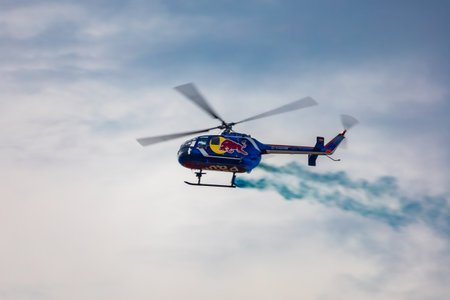 Leszno, Poland - June 16 2023: Antidotum Airshow Leszno 2023 and acrobatic shows full of smoke of Felix Baumgartner flying by helicopter Red Bull Bo 105 on a cloudy skyのeditorial素材