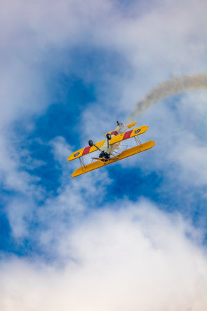 Leszno, Poland - June 17 2023: Antidotum Airshow Leszno 2023 and acrobatic shows of yellow Boeing Stearman plane on a blue clouy skyのeditorial素材