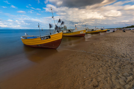 Sopot, Poland - July 22 2023: Row of few colorful boats hooked by rope and standing at coast of the beach at windy dayのeditorial素材