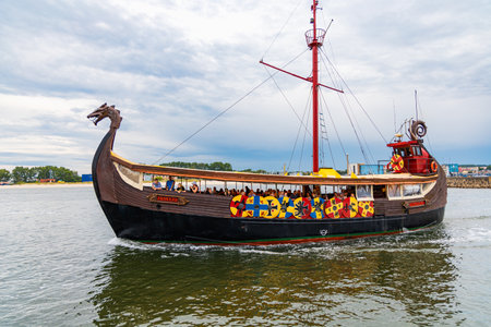 Wladyslawowo, Poland - July 24 2023: Beautiful wooden viking boat Rakkar with decorations around full of tourists at Baltic sea at cloudy dayのeditorial素材