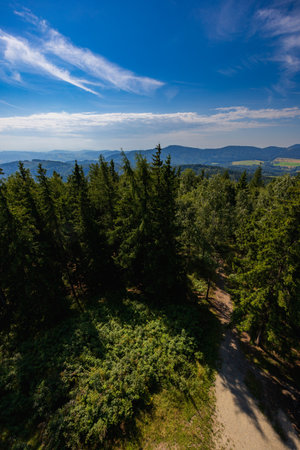 Beautiful green and blue panorama of layers of mountains and trees and some fields seen from top of...