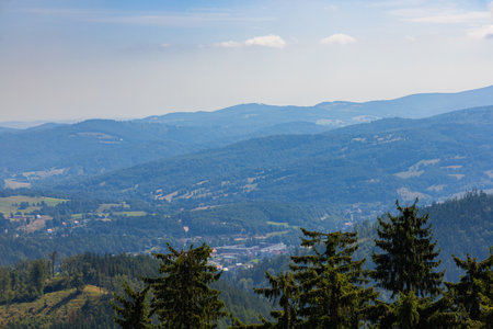 Beautiful green and blue panorama of layers of mountains and trees and some fields seen from top of viewing tower at highest mountain in this areaの写真素材